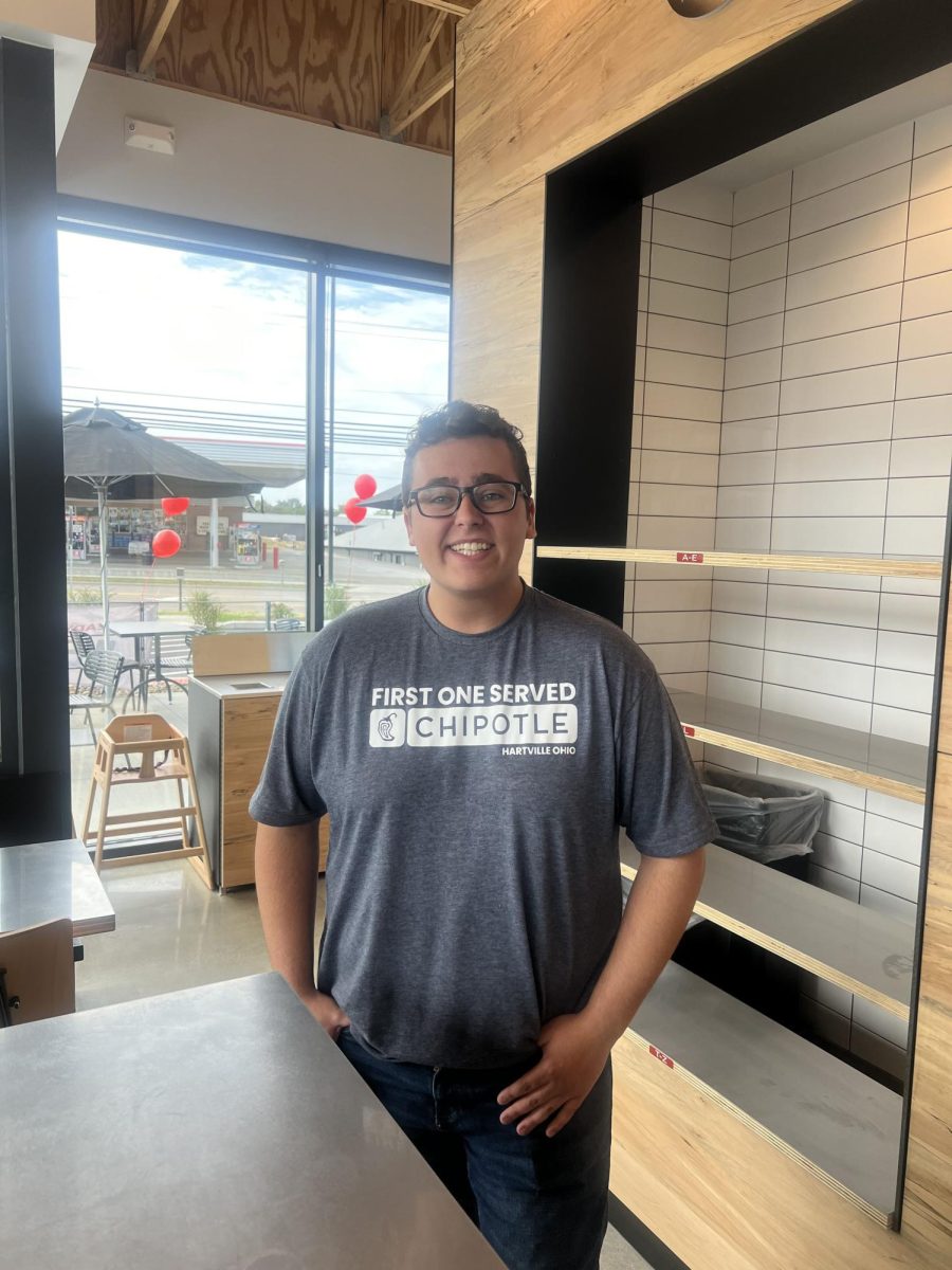 Noah Carter smiles proudly with a self-made shirt declaring his status as first customer at Chipotle on Sept 17, 2024. 